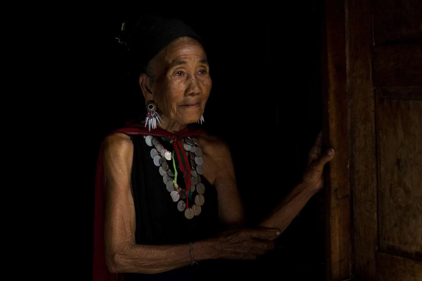 A woman from Myanmar's Kayah tribe sits in the doorway of her home.