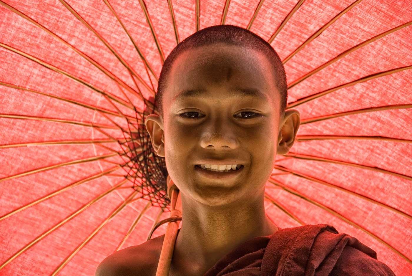 Postcard-perfect smiles as a monk shelters from the burning sun beneath his parasol.