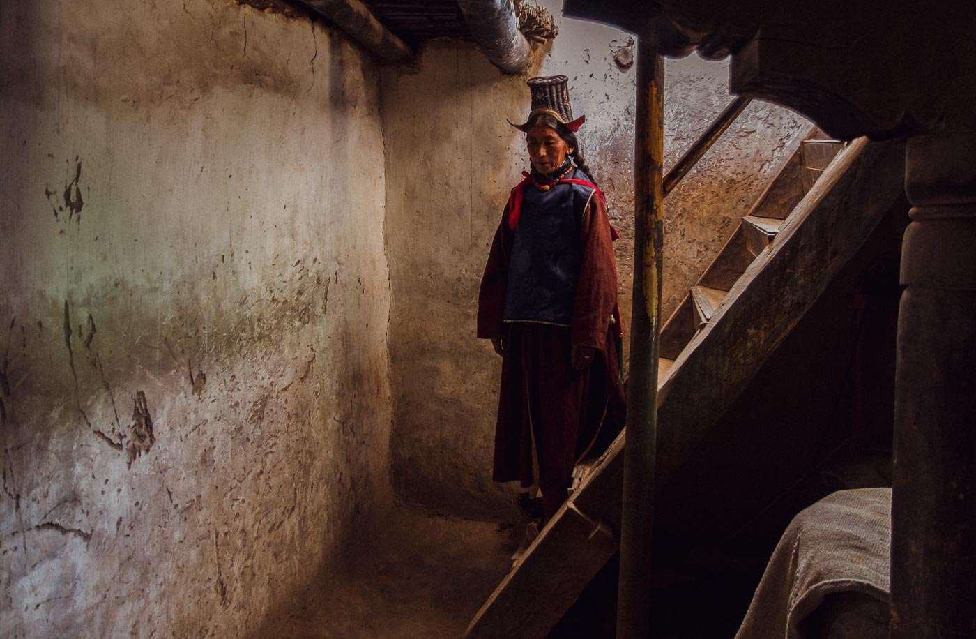 A Ladakhi woman pauses on the stairs at home.